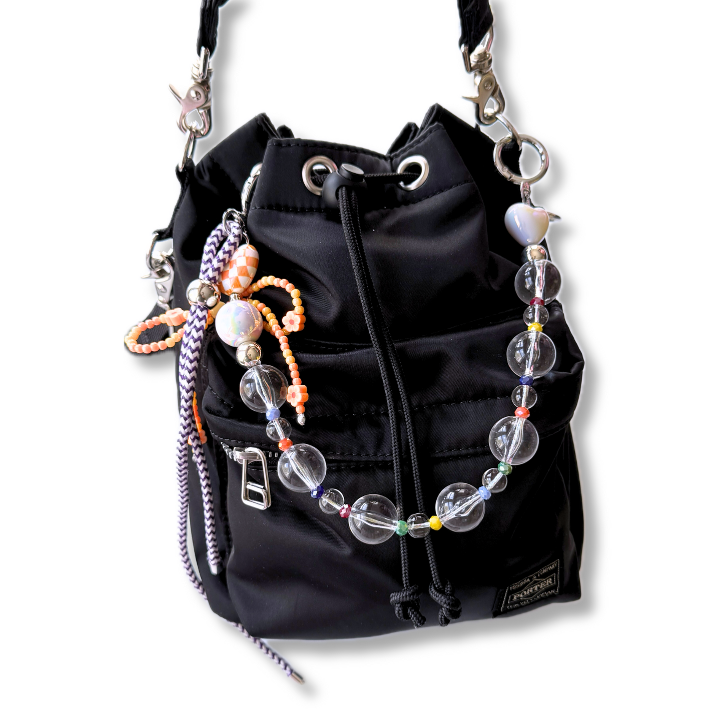 A beautiful aesthetically pleasing beaded bag charm featuring transparent and sparkling color beads decorating a black bucket bag.