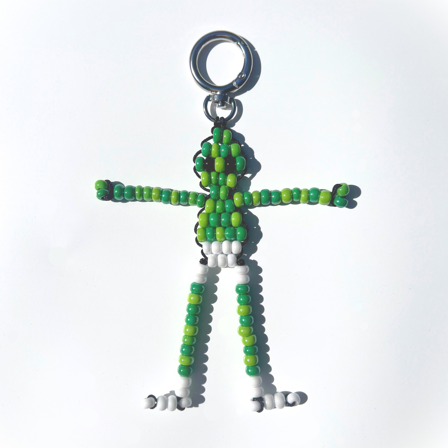 Front view of a handmade Beaded Green Martian Bag Charm featuring glossy green and white beads, silver-tone ring clasp, and playful alien design.