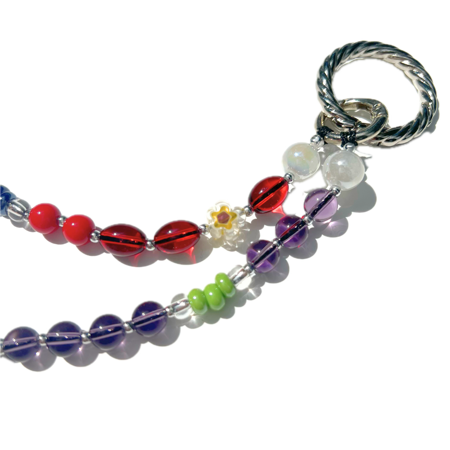 Close-up of cherry red and purple eclectic beaded charm showing daisy detail, green accents, iridescent beads, and twist clasp, handmade with glass, Czech, millefiori, and acrylic beads.