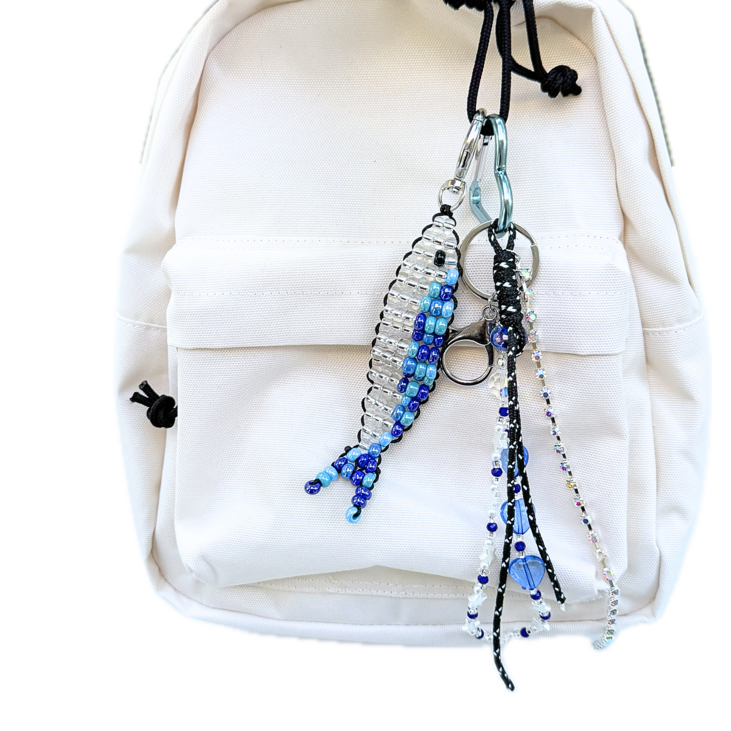 Beaded Blue Sardine Bag Charm clipped to a cream backpack, styled with another y2k inspired layered charm, showing how the handmade keychain adds a playful yet stylish accent.