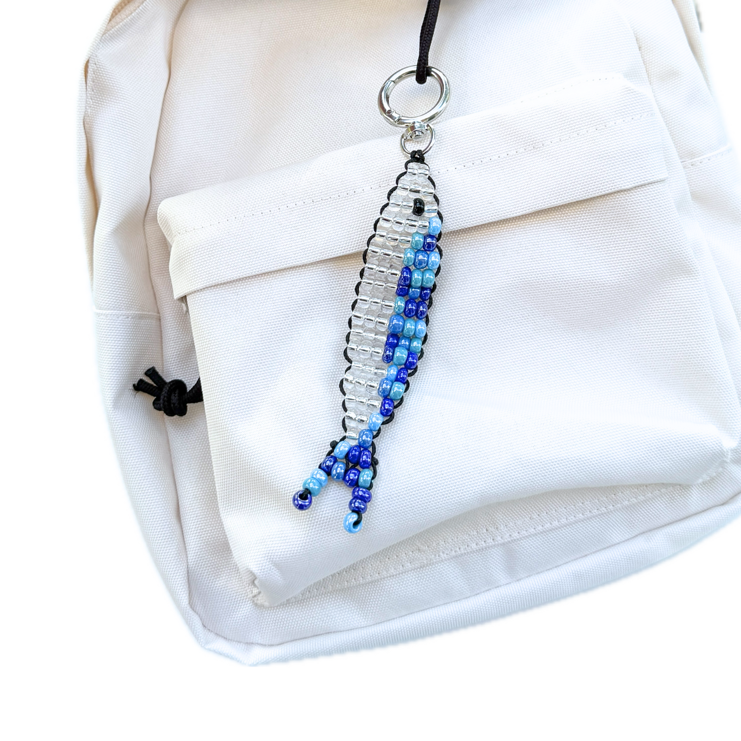 Beaded Blue Sardine Bag Charm clipped to a cream backpack, showing how the handmade keychain adds a playful yet stylish accent.