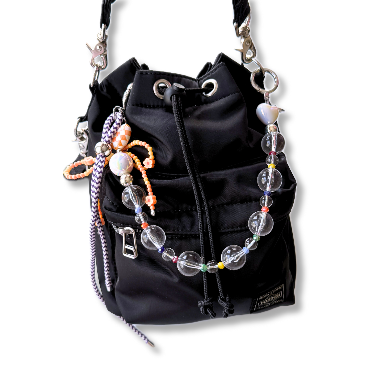 A beautiful aesthetically pleasing beaded bag charm featuring transparent and sparkling color beads decorating a black bucket bag. 