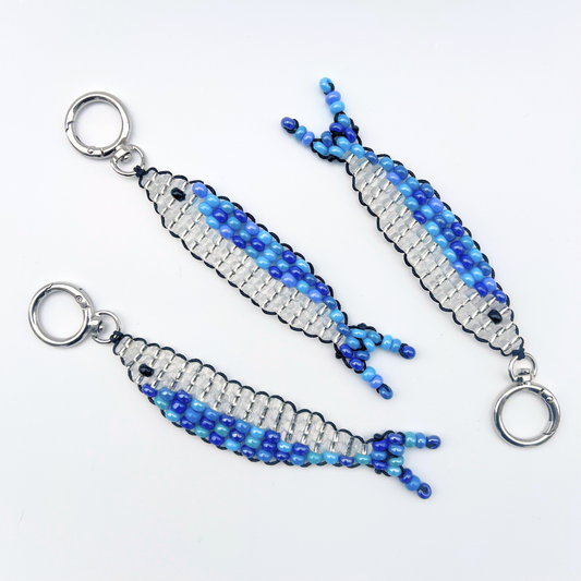Three handmade blue and silver beaded sardine fish bag charms laid flat on a white background with metal keyrings.