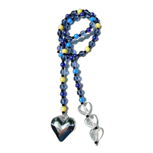 The Chrome Silver Heart Bag Charm arranged in a looped display, showcasing midnight blue, yellow, and clear beads with a reflective silver heart pendant and clear crystal heart details.
