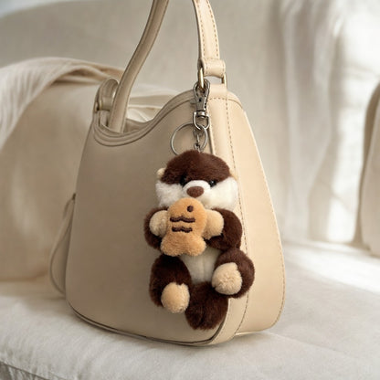 Dark brown sea otter plush bag charm holding taiyaki clipped to a handbag. Cute Japanese character keychain