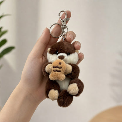 Kawaii dark brown sea otter Rakko-san plush keychain holding a taiyaki, shown in hand for scale (approx. 7.5 inches)