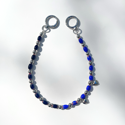 Single Modern Romantic Beaded Bag Charm displayed on a white surface, showing alternating black and blue chevron glass beads with silver heart details and chrome clasp.