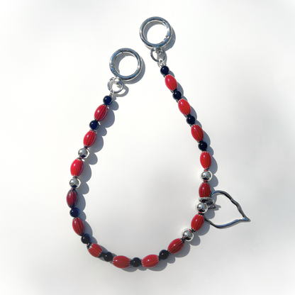 Single Modern Romantic Beaded Bag Charm shown flat on a white surface, highlighting the red chevron glass beads, black accents, and silver heart charm with chrome clasp.