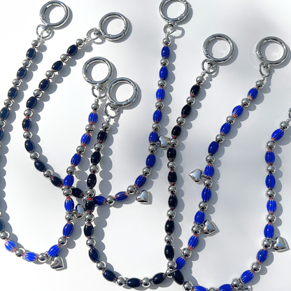 Group display of Modern Romantic Beaded Bag Charms in black and blue tones arranged together, highlighting glass beads, silver hearts, and reflective chrome hardware.