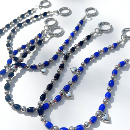 Multiple Modern Romantic Beaded Bag Charms featuring deep blue and black chevron glass beads with silver heart accents and chrome hardware on a white background.