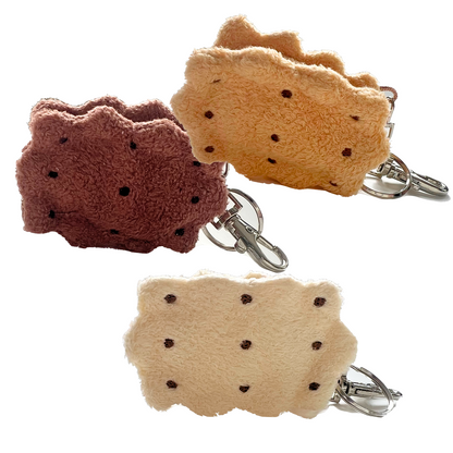 Back view of three sandwich cookie plush keychains in chocolate, honey, and vanilla colors, showing embroidered chocolate chip details and silver clasps.
