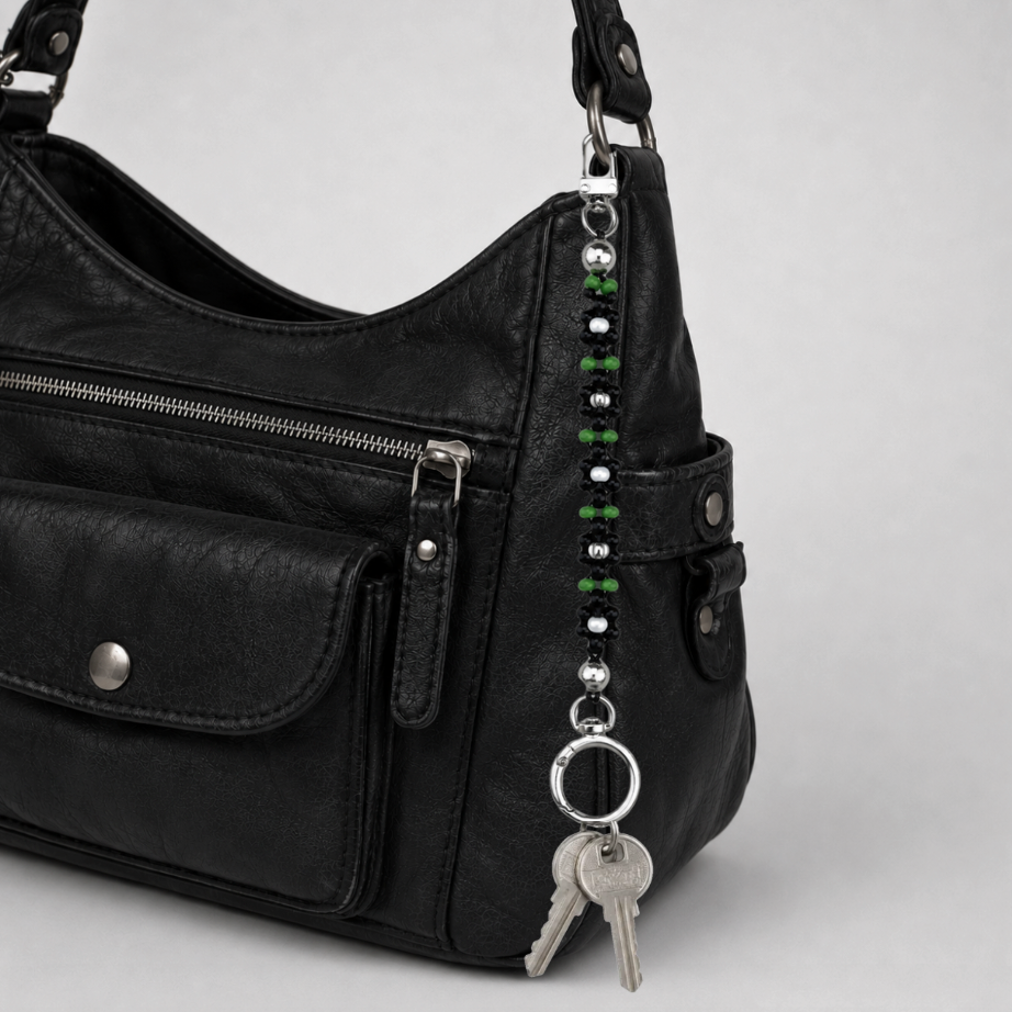 Handmade black daisy beaded bag charm clipped to black leather handbag – elegant multi-use keychain for designer and everyday bags