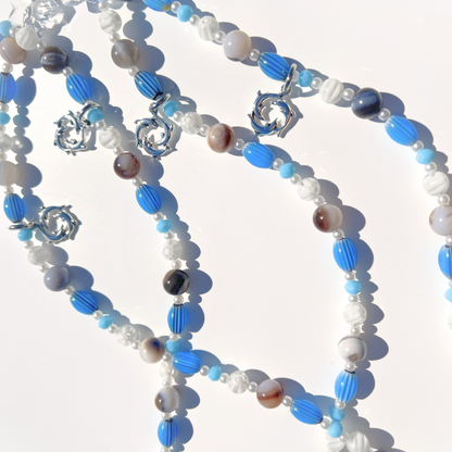 Close up of Coastal Muse Marina Blue bag charm showing blue beads, agate stones, and triple dolphin pendant detail