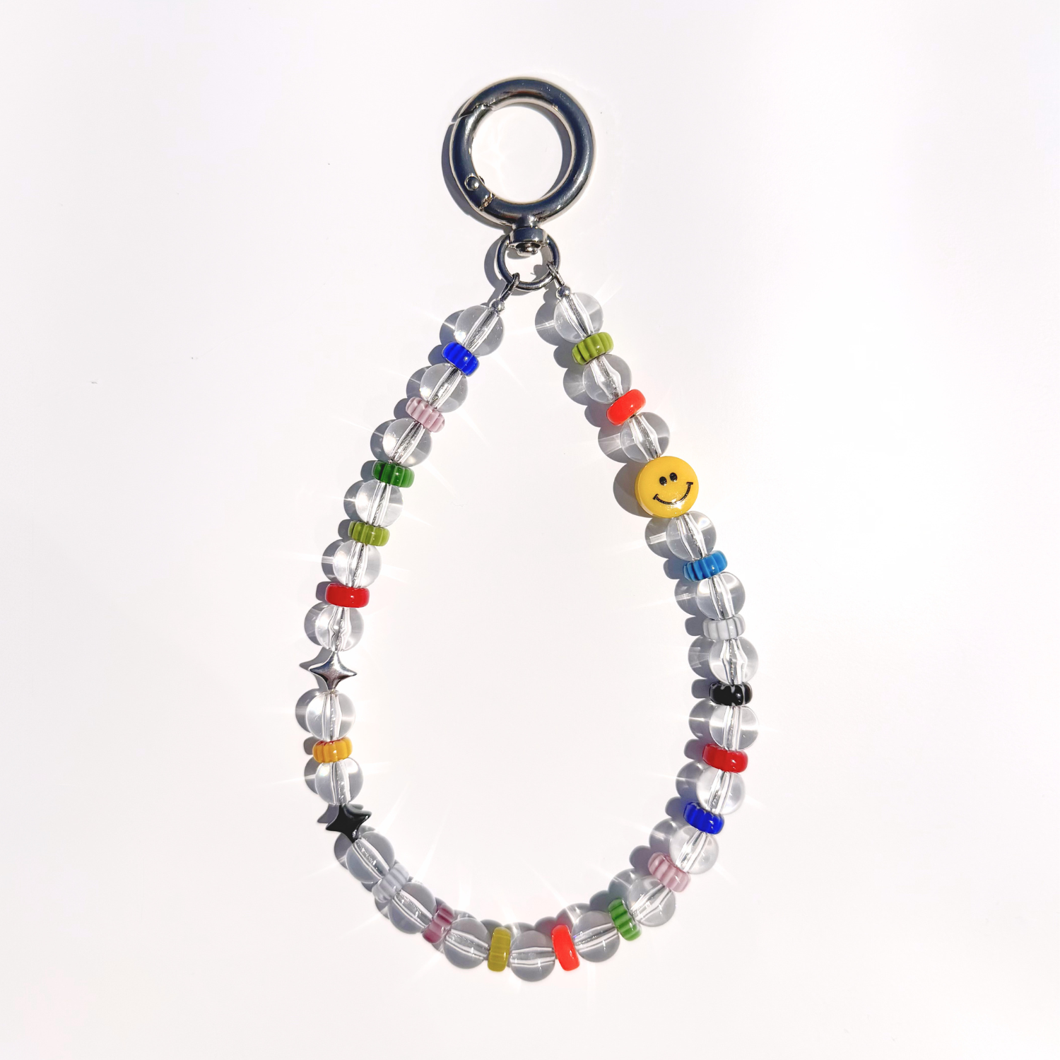 A single Solar Joy Beaded Bag Charm with clear beads, colorful rings, silver stars, and a yellow smiley bead, displayed on a white background under natural light.