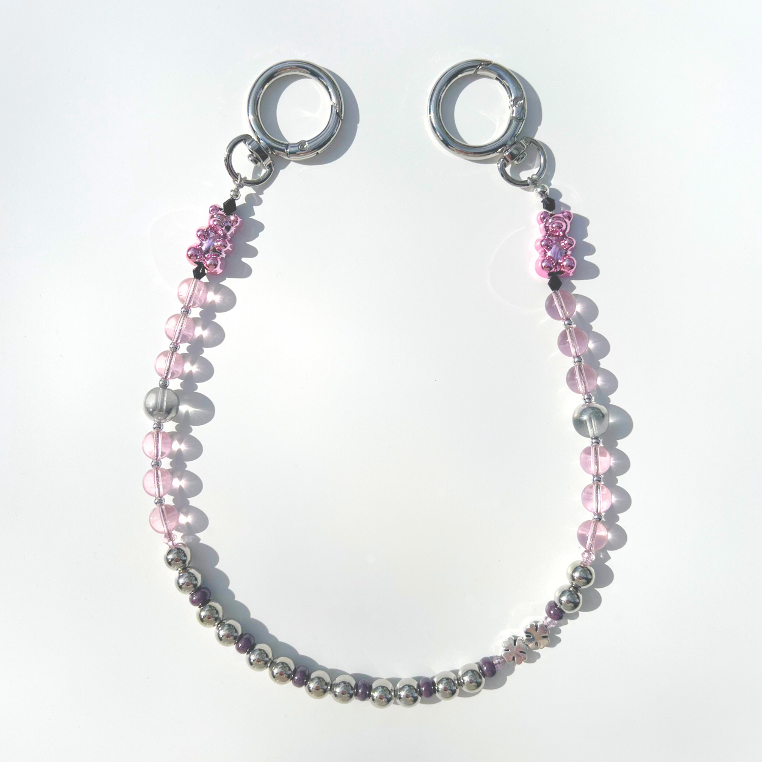 A pink beaded bag charm with chrome accents and a pink gummy bear bead displayed on a white background.
