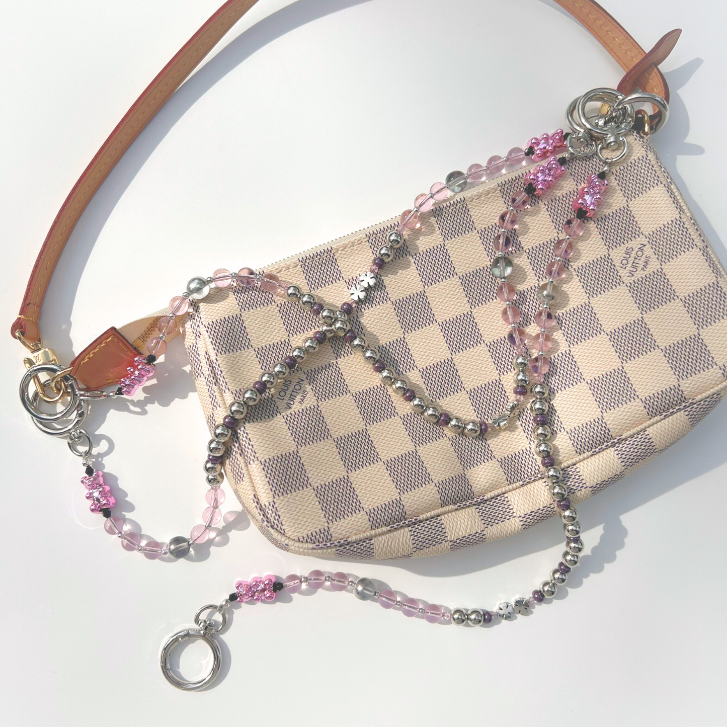 Pink beaded bag charm attached to a checkered mini bag, showing pink beads, chrome beads, and gummy bear accents.
