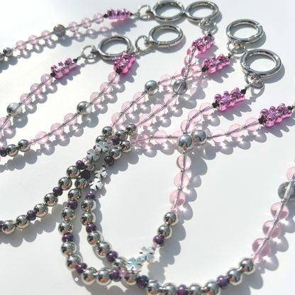 Multiple pink beaded bag charms arranged together, featuring pink glass beads, chrome beads, and pink gummy bear accents.