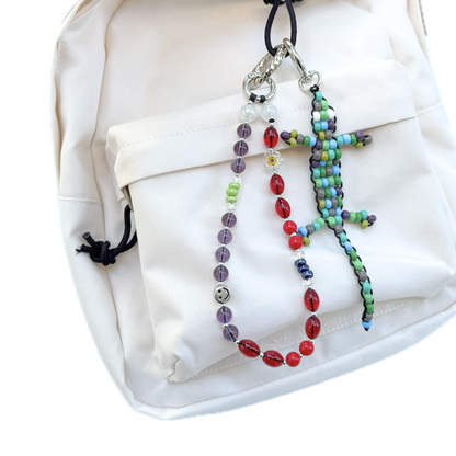 Beaded Green Gecko Bag Charm attached to a white backpack alongside other beaded charms, showing its colorful handmade lizard design in use.