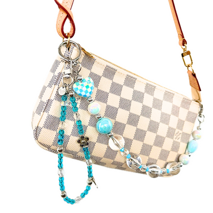 Blue beaded dolphin bag charm clipped to a cream checkered pochette. 
Cute y2k pop star blue bag charm, perfect gift for friends
