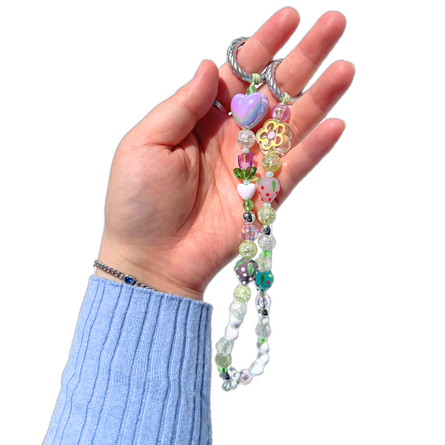 A hand holding a colorful, handcrafted beaded bag charm made with heart-shaped, floral, and fruit-themed beads in soft pastel tones. Perfect for decorating tote bags or handbags.