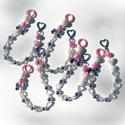 Multiple Kawaii Pink Beaded Bag Charms arranged together on a white surface, showing their heart clasps, metallic silver bows, and glossy pink beads sparkling in the light.