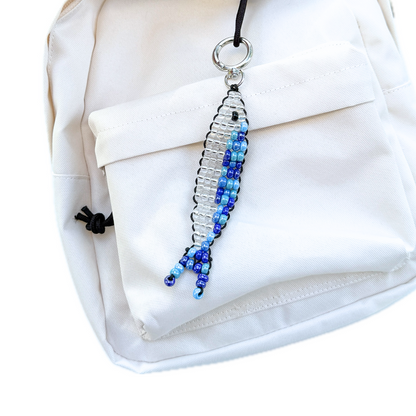 Beaded Blue Sardine Bag Charm clipped to a cream backpack, showing how the handmade keychain adds a playful yet stylish accent.
